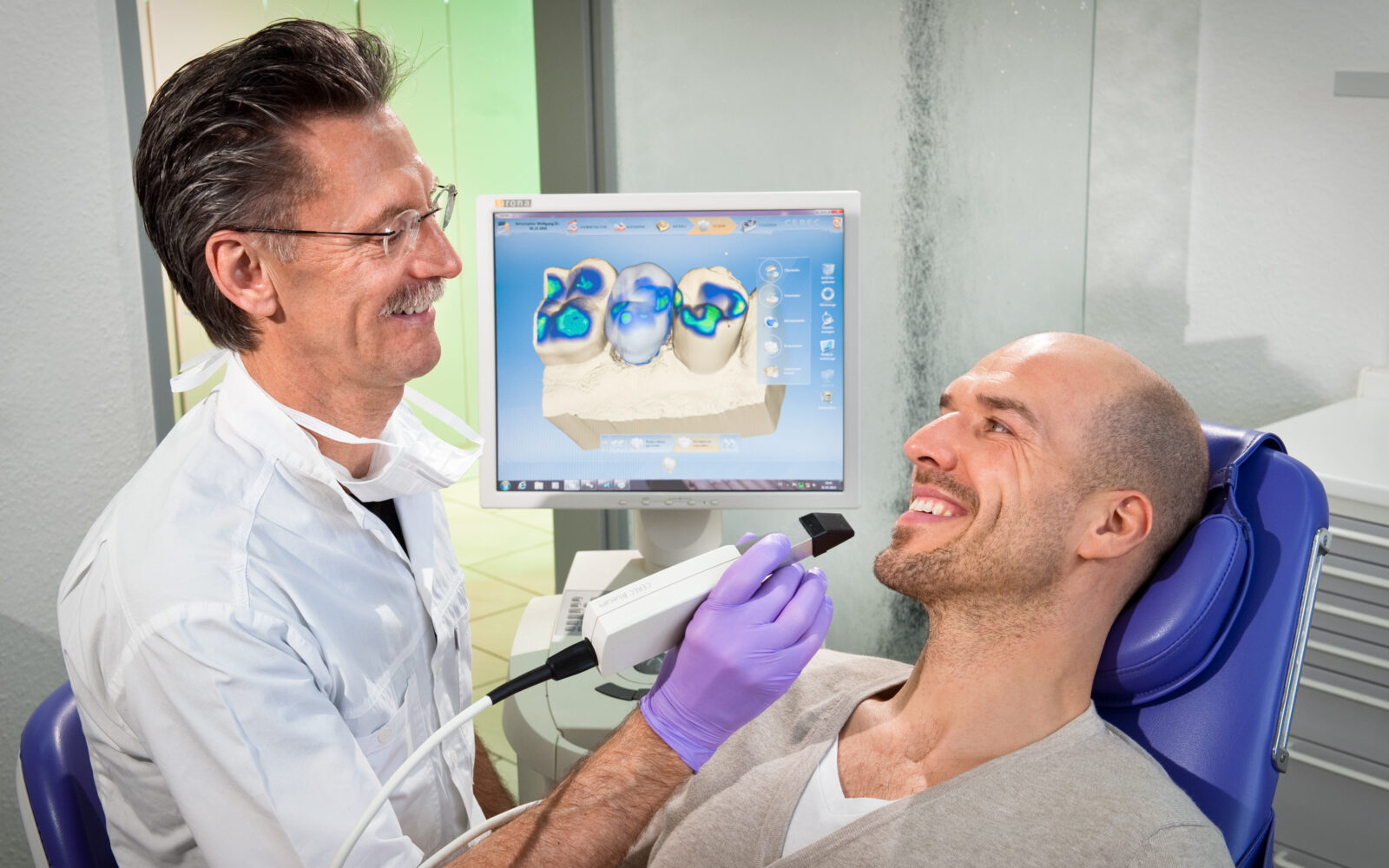 Zahnarzt mit dem intraoralen Scanner am Patienten - im Hintergrund der CEREC Monitor. Praxis Dr. Martin in Betzdorf. Foto Dietrich Hackenberg - lichtbild.org